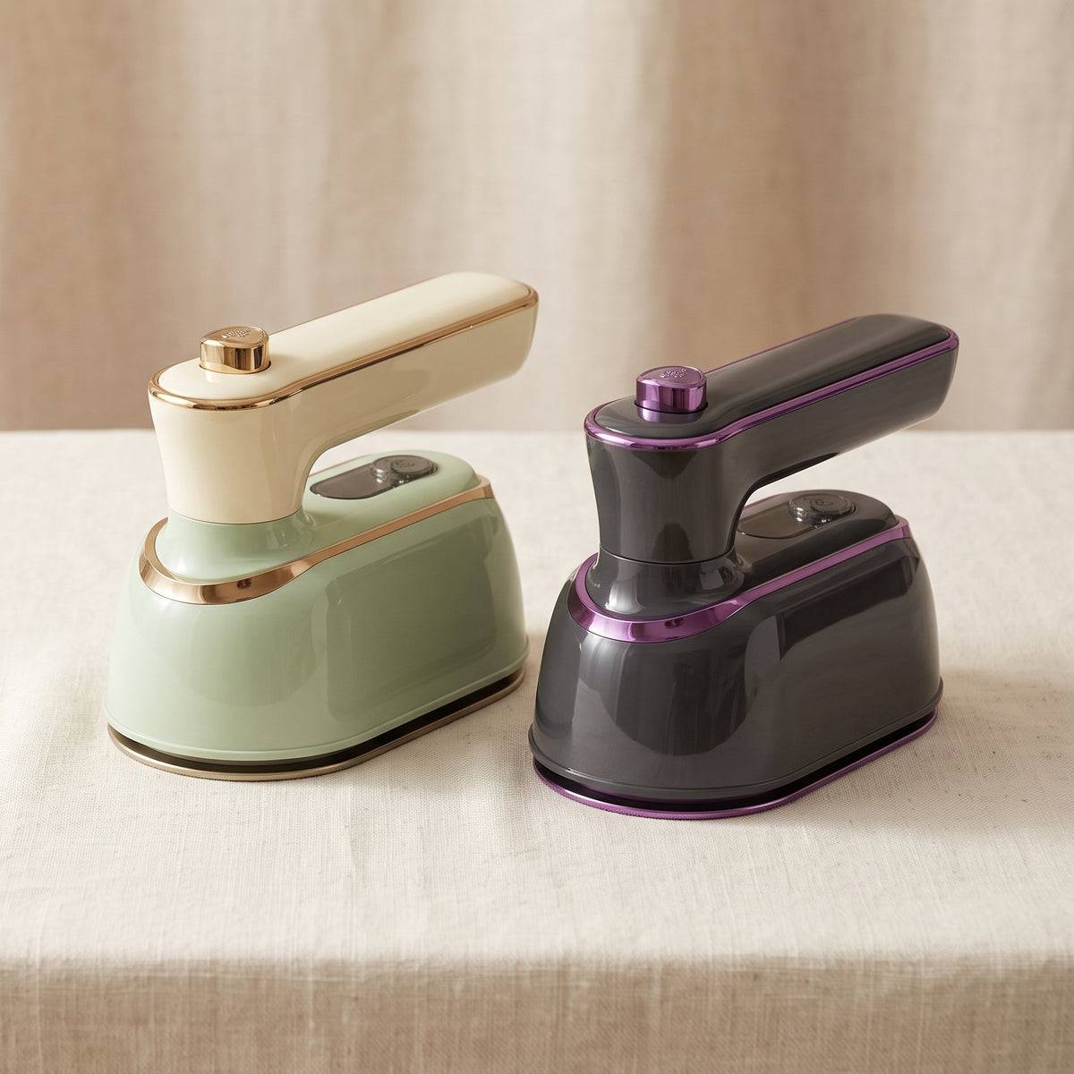The mini steam iron in Sage and in Charcoal, side by side